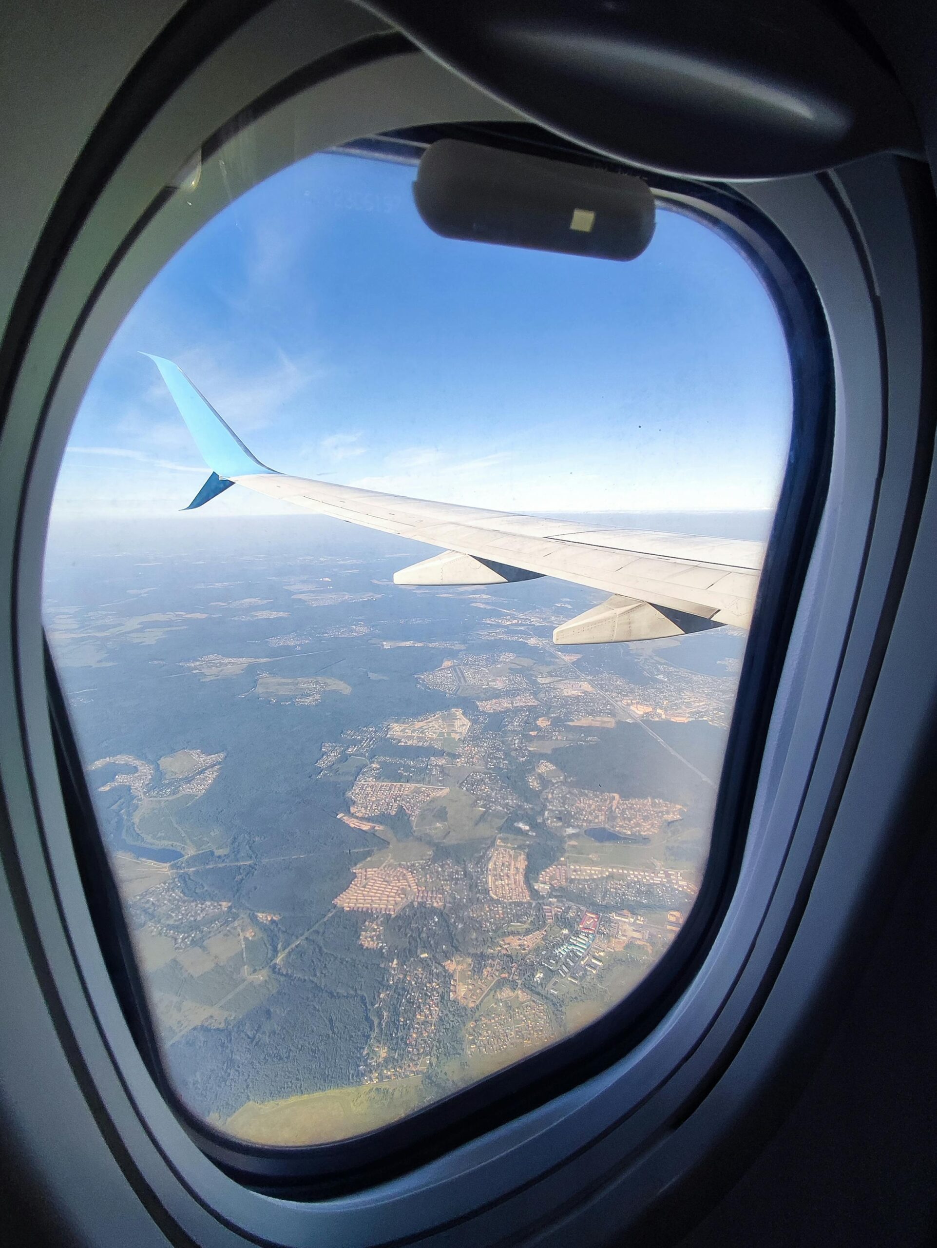 A stunning view of the landscape through an airplane window, showcasing the aircraft wing.