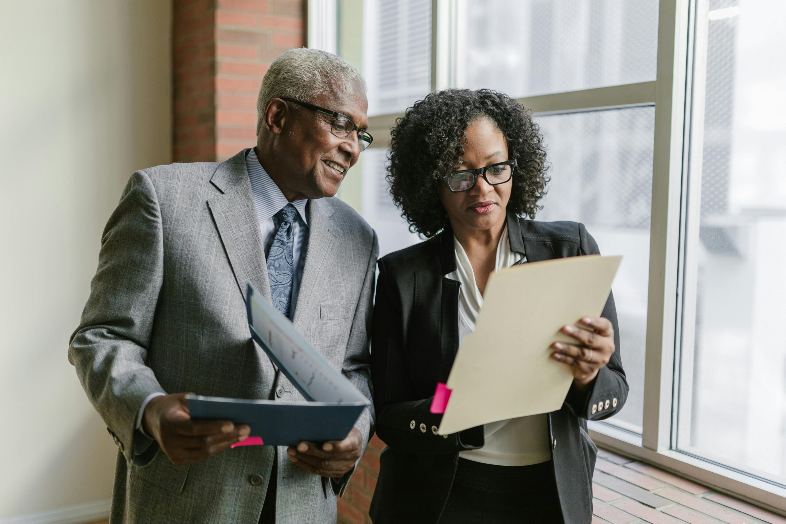 Two business professionals reviewing documents in a corporate office setting.
